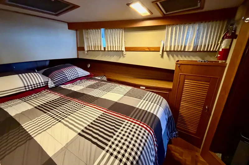 Slide: The Image of Cozy bedroom interior of 1991 Grand Banks 36 Europa yacht with plaid bedding and wooden cabinetry. - 34