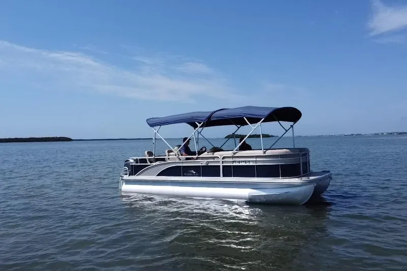 Slide: The Image of 2015 Bennington 22 SSX pontoon boat cruising on a calm lake under a clear blue sky. - 19