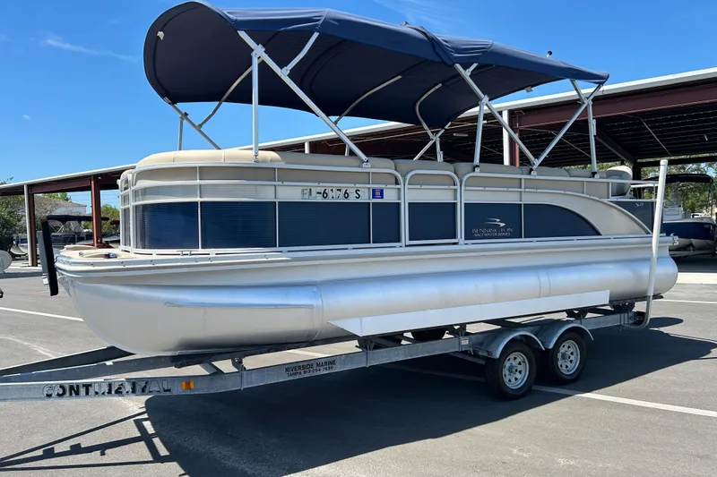 Slide: The Image of 2015 Bennington 22 SSX pontoon boat on trailer with blue canopy in parking lot. - 5