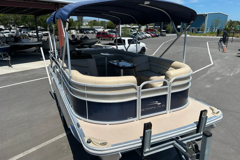 Slide: The Image of 2015 Bennington 22 SSX pontoon boat with canopy, parked on a trailer in a marina. - 6