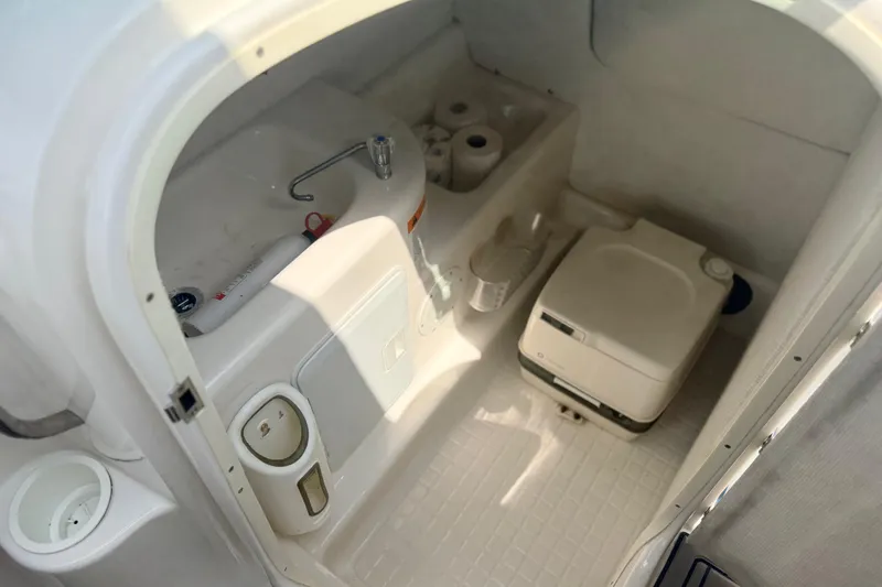 Slide: The Image of Interior of a 2000 Chris Craft 262 Sport Deck boat, featuring a compact bathroom setup. - 25