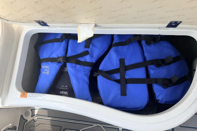 Slide: The Image of Storage compartment with blue life jackets on a 2000 Chris Craft 262 Sport Deck boat. - 26