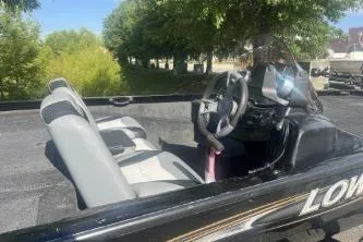Slide: The Image of 2016 Lowe Stinger 180 boat interior with steering wheel and seating, surrounded by greenery. - 5