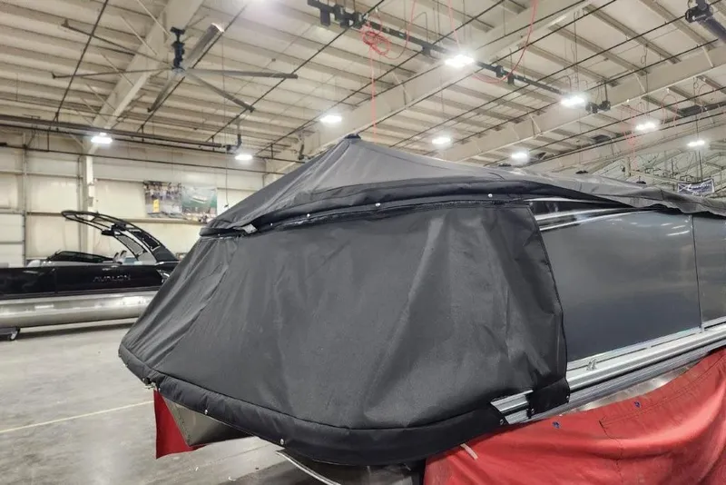 Slide: The Image of 2026 Tahoe Pontoon 1985 LTZ Cruise covered in a protective tarp inside a warehouse. - 11