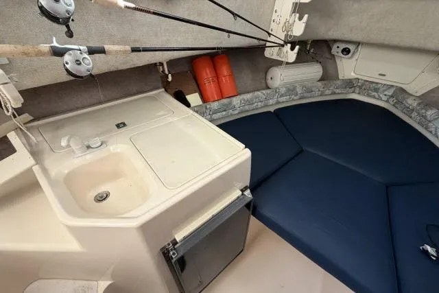 Slide: The Image of 1996 Grady-White Sailfish 272 cabin interior with sink, fishing rods, and blue cushions. - 22