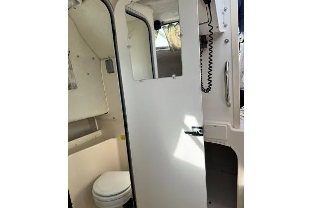 Slide: The Image of Interior of 1996 Grady-White Sailfish 272 boat, featuring a compact bathroom with toilet. - 28