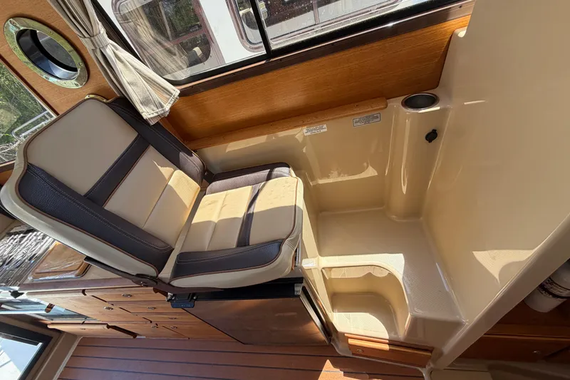 Slide: The Image of Interior seating of 2018 Ranger Tugs R-27 boat, featuring wood accents and beige upholstery. - 13