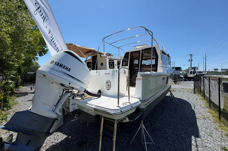 Slide: The Image of 2018 Ranger Tugs R-27 boat with Yamaha outboard motor, parked on gravel under clear sky. - 2