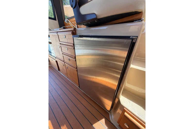 Slide: The Image of Interior of 2018 Ranger Tugs R-27 with stainless steel fridge and wooden cabinetry. - 8