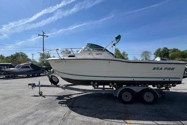 Slide: The Image of 2001 Seapro 235 WAC boat on trailer in parking lot under clear sky. - 2