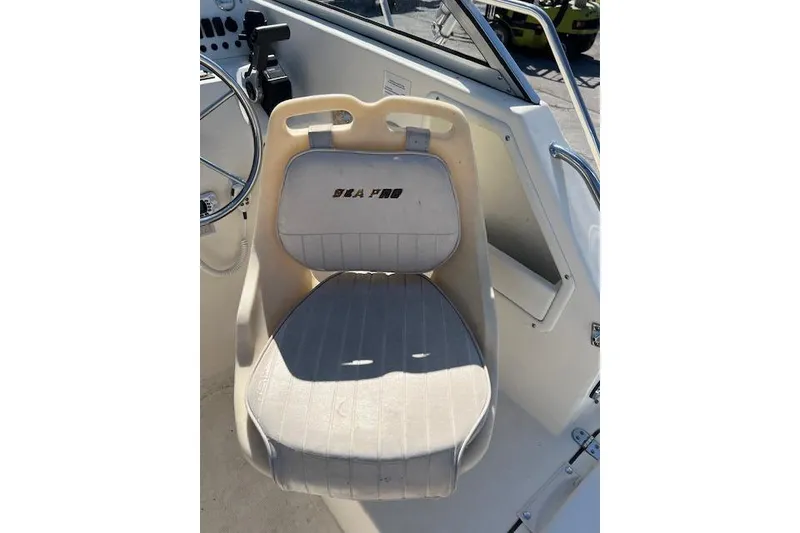 Slide: The Image of Captain's seat on 2001 Seapro 235 WAC boat, featuring white upholstery and steering wheel. - 9
