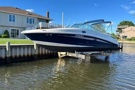 The Image of 2011 Sea Ray 300 Sundeck boat docked by waterfront homes under clear blue sky. - 0