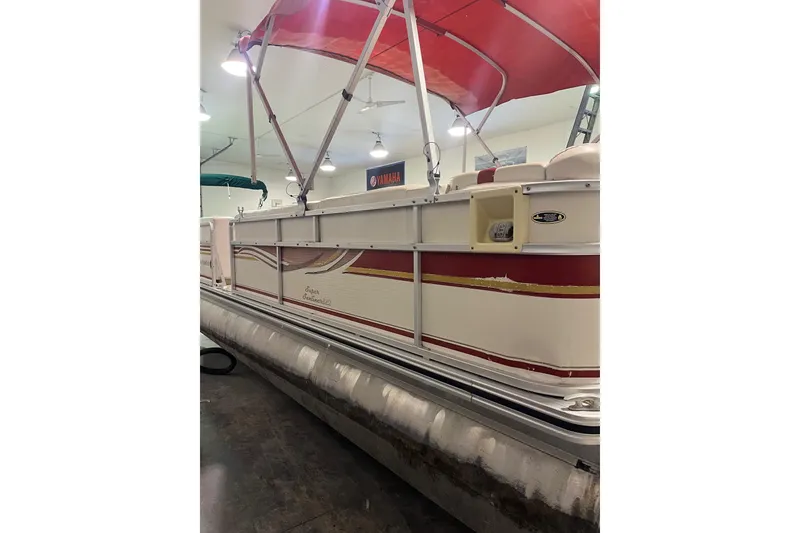 Slide: The Image of 2002 Harris FloteBote 220 Super Sunliner pontoon boat with red canopy in indoor storage. - 9