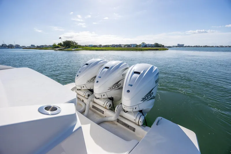 Slide: The Image of 2022 Tiara Yachts 43 LE with triple outboard engines on a serene waterway. - 30