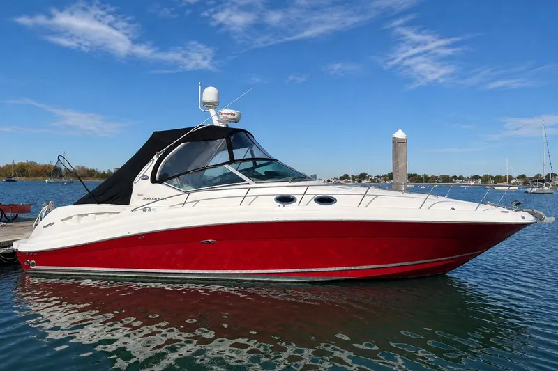 The Image of 2006 Sea Ray 340 Sundancer yacht at sunset with city skyline backdrop. - 0