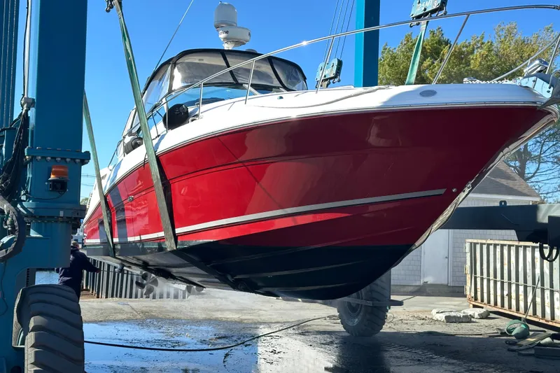 Slide: The Image of 2006 Sea Ray 340 Sundancer boat in dry dock, vibrant red hull, being serviced. - 2