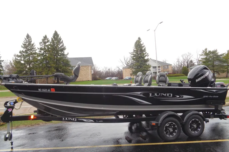 The Image of 2011 Lund 2010 Pro Guide boat on trailer, parked outdoors on a rainy day. - 0