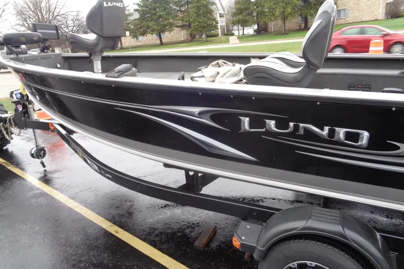 Slide: The Image of 2011 Lund 2010 Pro Guide boat on trailer, black exterior, parked on wet pavement. - 3