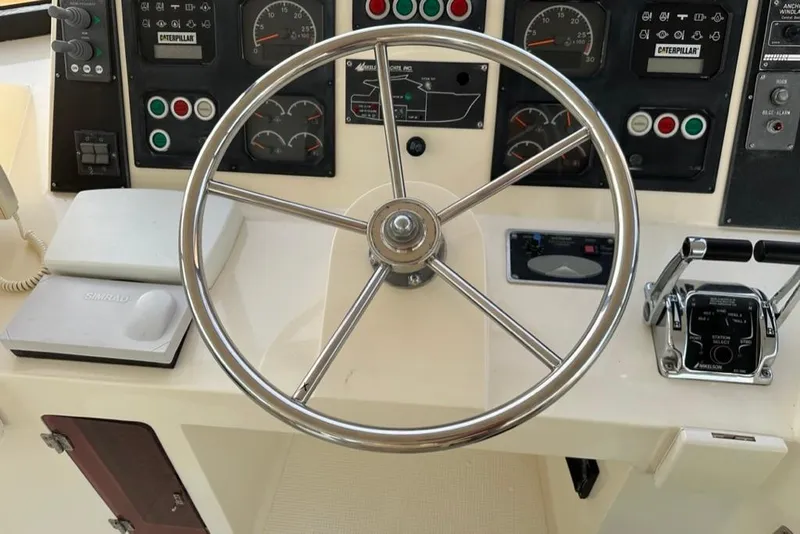 Slide: The Image of Steering wheel and controls of a 1999 Mikelson 64 Long Range Luxury Sportfish yacht. - 50