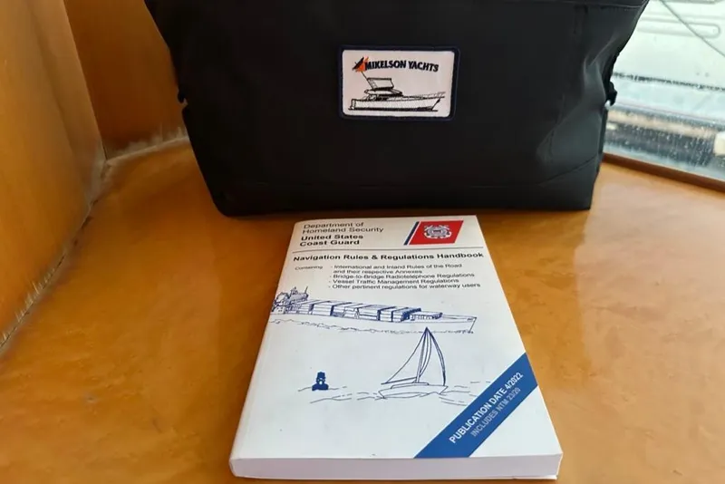 Slide: The Image of Navigation handbook on a Mikelson 64 Long Range Luxury Sportfish, 1999 model, with branded bag. - 56
