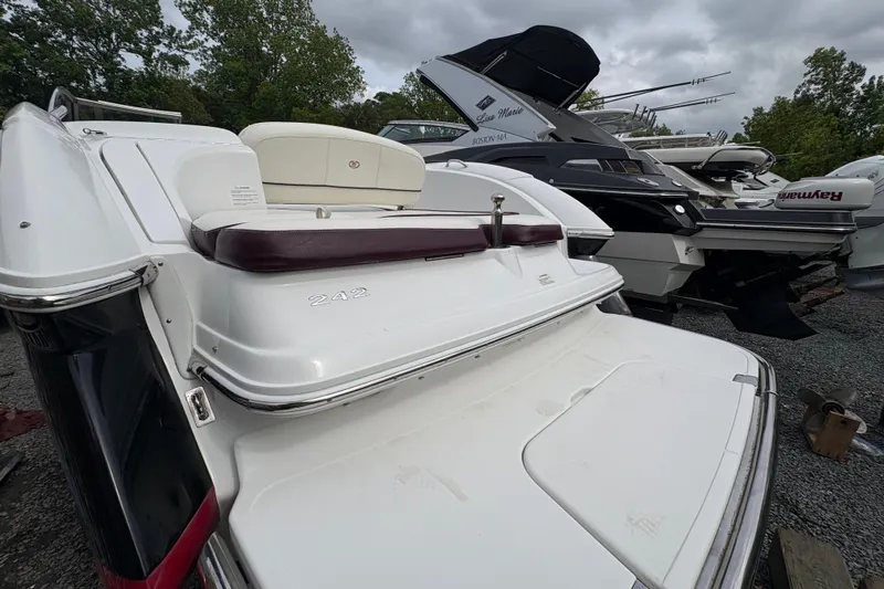 Slide: The Image of 2013 Cobalt 242 boat with white and maroon seating, parked among other boats. - 13