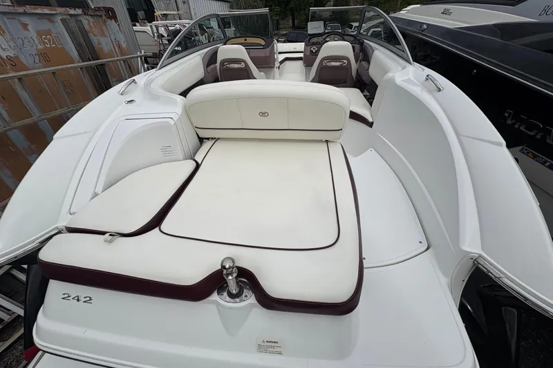 Slide: The Image of 2013 Cobalt 242 boat with white and maroon seating, parked among other boats. - 15