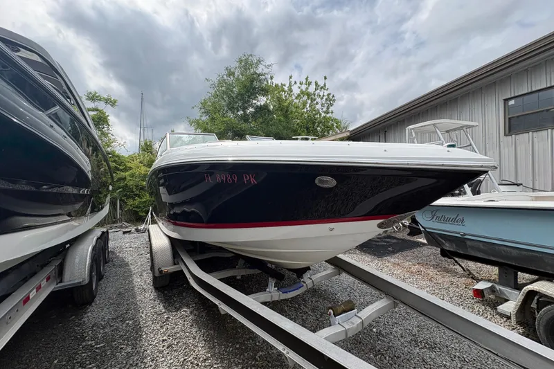 Slide: The Image of 2013 Cobalt 242 boat on trailer, parked outdoors near other boats. - 2