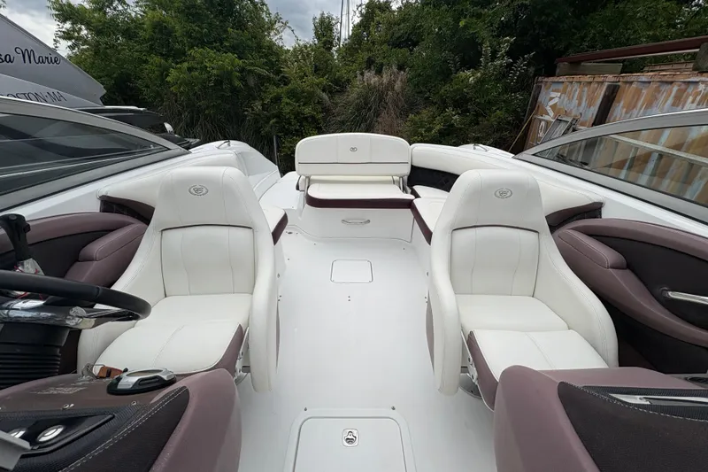 Slide: The Image of 2013 Cobalt 242 boat interior with white and brown seating, surrounded by lush greenery. - 6