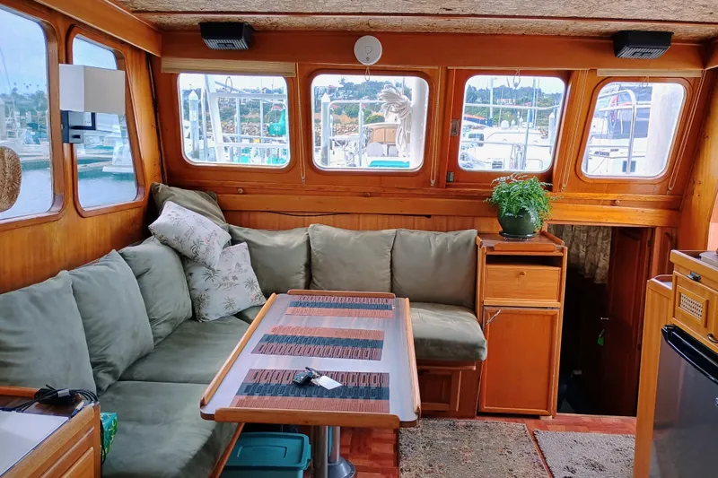 Slide: The Image of Cozy 1978 Californian LRC boat interior with green sofa, wooden table, and potted plant. - 21