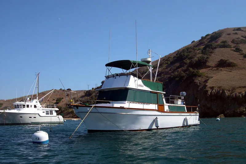 Slide: The Image of 1978 Californian 42 LRC yacht anchored near a scenic coastal hillside. - 38