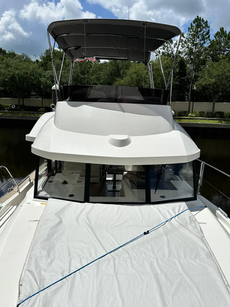 Slide: The Image of 2022 Beneteau Swift Trawler 35 with covered deck, docked under a cloudy sky. - 24