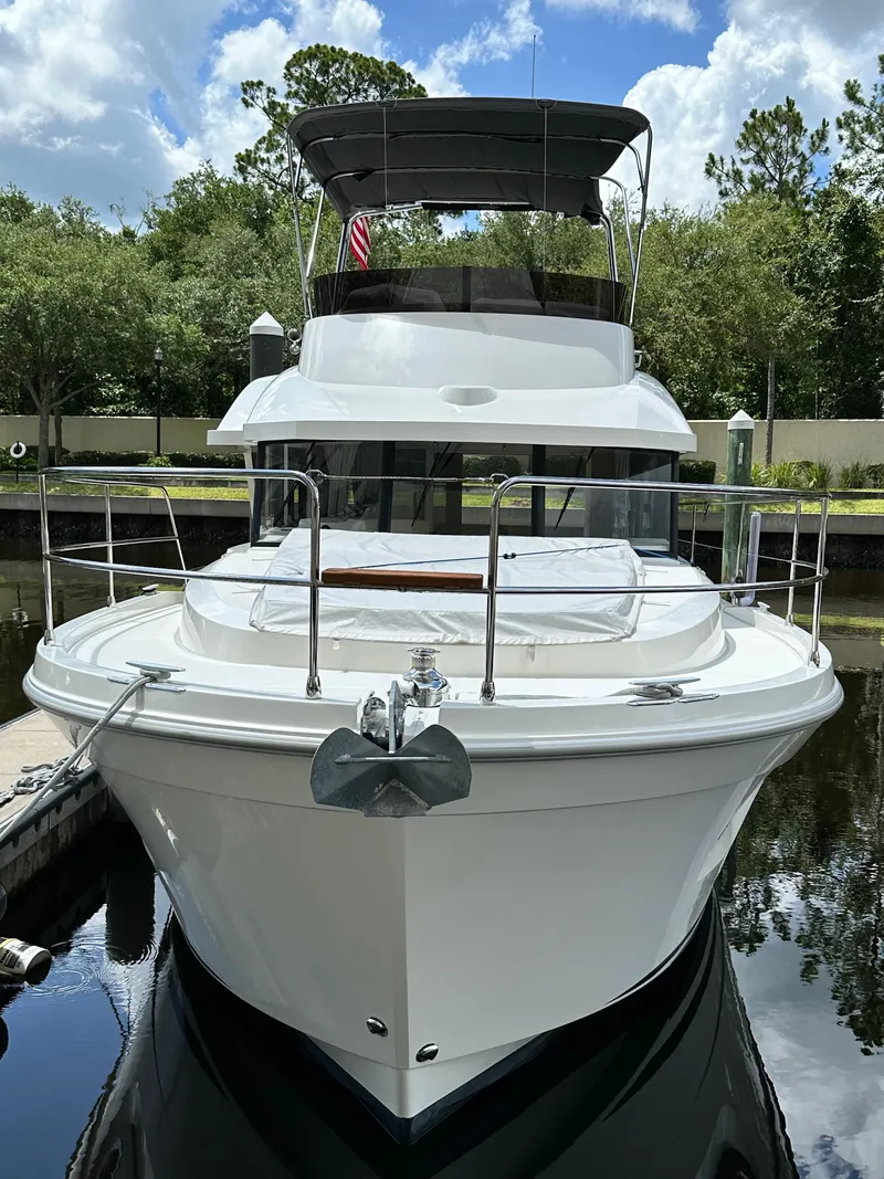 Slide: The Image of 2022 Beneteau Swift Trawler 35 docked, front view, surrounded by trees and blue sky. - 3