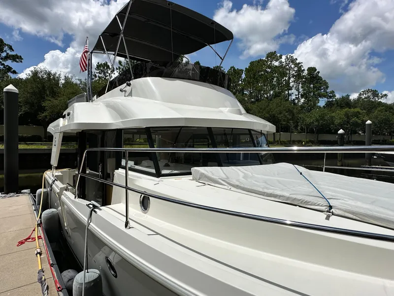 Slide: The Image of 2022 Beneteau Swift Trawler 35 docked, featuring sleek design and spacious deck under a cloudy sky. - 5