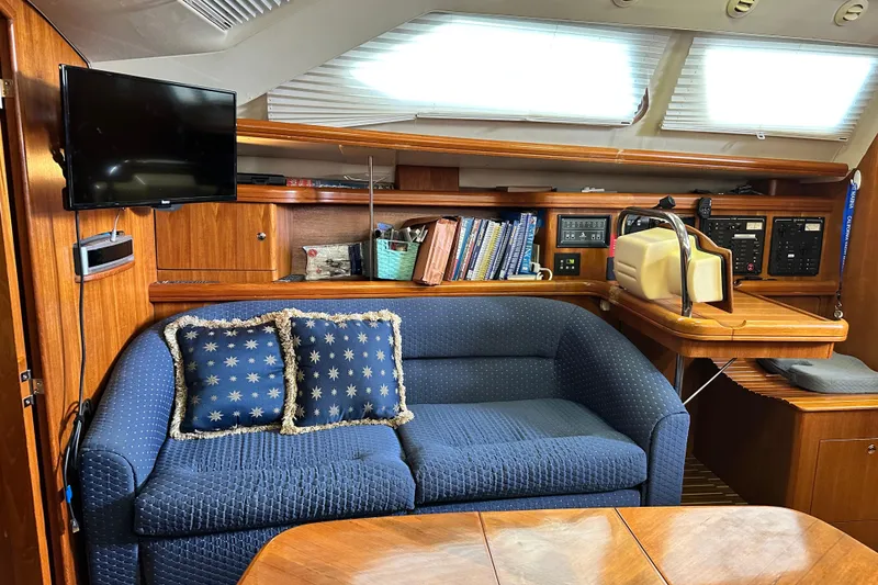 Slide: The Image of Interior of 2006 Hunter 41 Deck Salon with blue sofa, TV, and navigation station. - 50