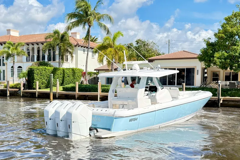 Slide: The Image of 2023 Intrepid 427 Nomad FE boat cruising near waterfront homes with palm trees. - 3