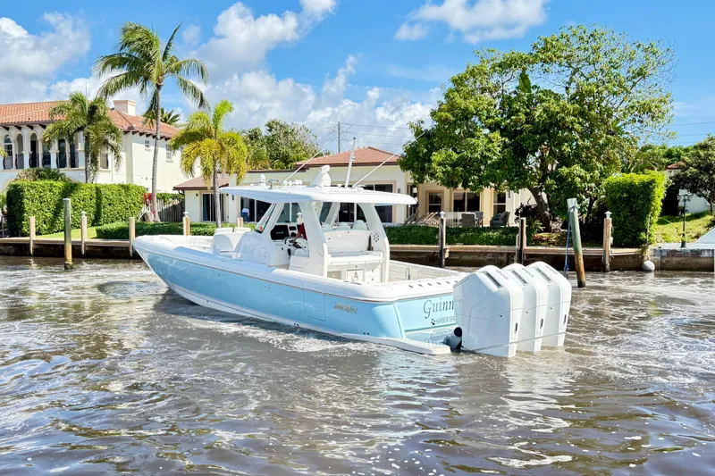 Slide: The Image of 2023 Intrepid 427 Nomad FE boat cruising near waterfront homes, under a clear blue sky. - 4