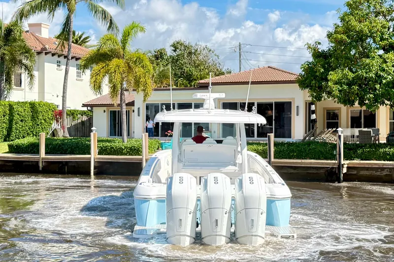 Slide: The Image of 2023 Intrepid 427 Nomad FE boat docked near waterfront home with palm trees. - 5
