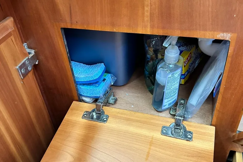 Slide: The Image of Wooden cabinet with cleaning supplies, sponges, and soap, in a 2007 Sabre 386. - 78
