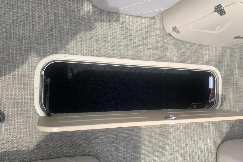 Slide: The Image of Open storage compartment on 2015 Avalon Windjammer Elite 25' boat with carpeted interior. - 18