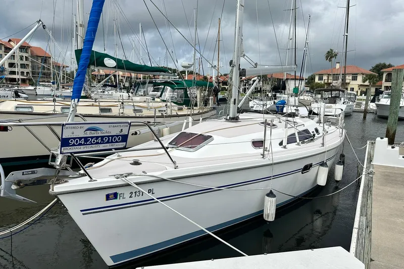 Slide: The Image of 2008 Catalina 320 sailboat docked at marina, overcast sky, brokerage sign visible. - 2