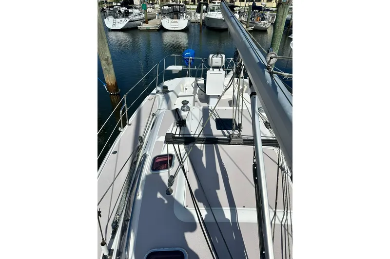 Slide: The Image of 2008 Catalina 320 sailboat deck view in marina, showcasing rigging and moored boats. - 27