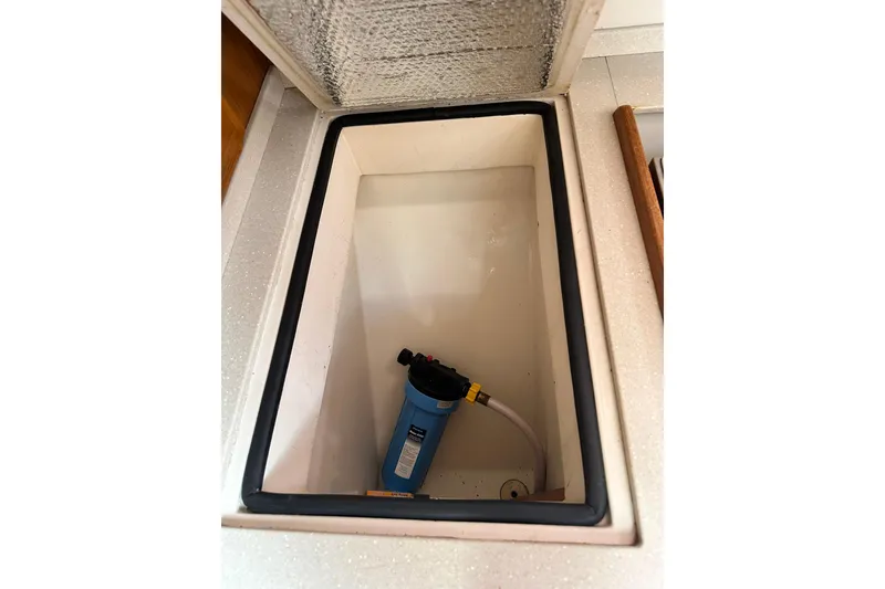 Slide: The Image of Open storage compartment in 2008 Catalina 320 boat with a blue water filter inside. - 68