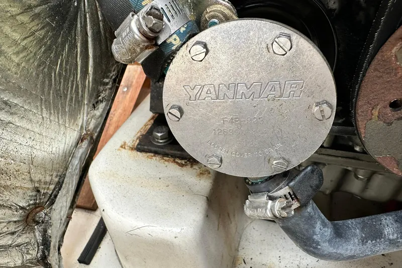 Slide: The Image of Yanmar engine component in a 2008 Catalina 320 sailboat, featuring metal cover and hoses. - 70