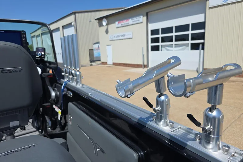 Slide: The Image of 2026 Yar-Craft 219TFX boat interior with rod holders, parked outside a garage. - 18