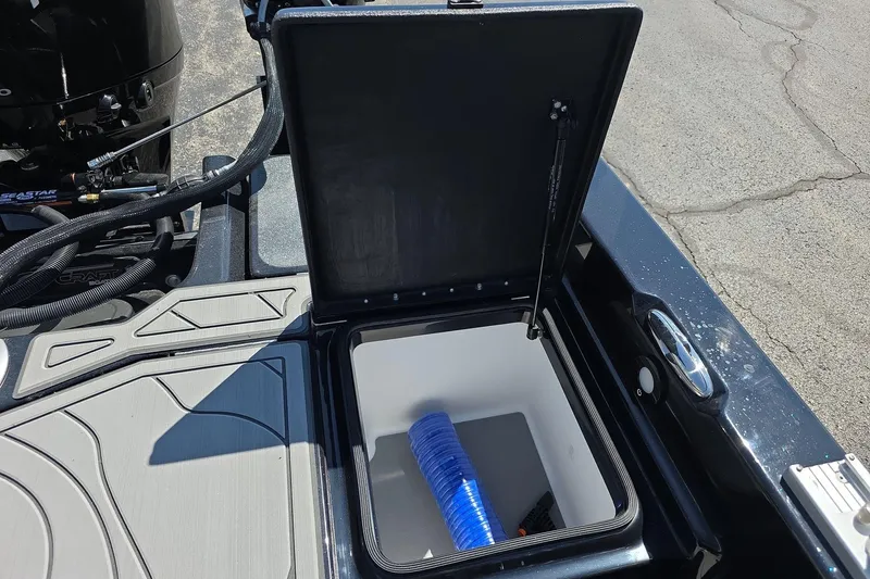 Slide: The Image of Open storage compartment on 2026 Yar-Craft 219TFX boat, featuring a blue hose inside. - 28