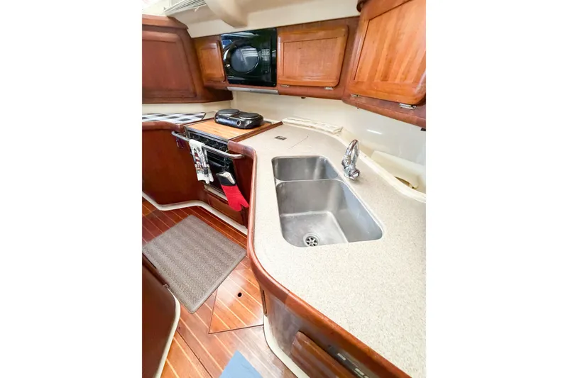 Slide: The Image of 1996 Hunter 430 yacht kitchen with wooden cabinets, dual sink, and stove. - 36
