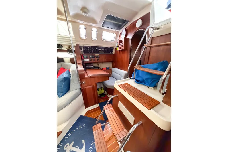 Slide: The Image of Interior of a 1996 Hunter 430 sailboat, featuring wooden steps and cozy seating. - 56