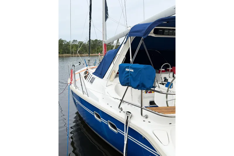 Slide: The Image of 1996 Hunter 430 sailboat docked, featuring blue and white design with covered equipment. - 89
