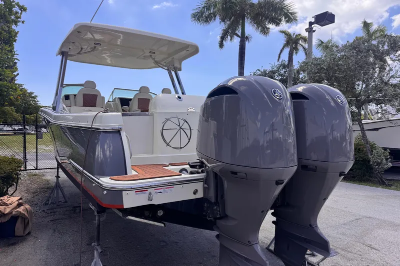Slide: The Image of 2018 Chris-Craft Calypso 30 boat with dual outboard engines, parked outdoors. - 2