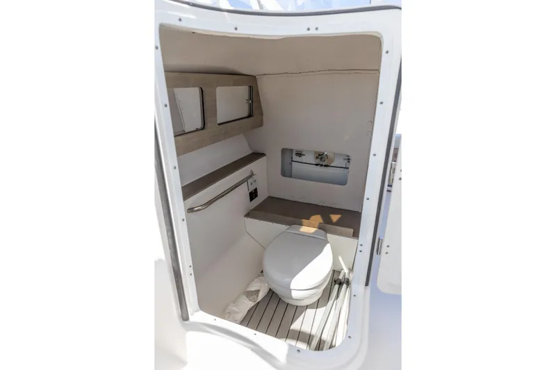 Slide: The Image of Interior of 2026 Edgewater 248CX Crossover boat, featuring a compact marine toilet. - 7